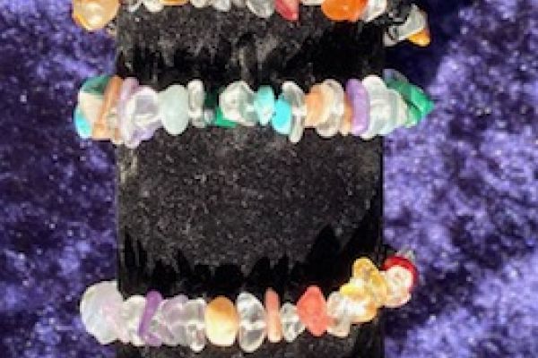 Zelfgemaakte edelstenen armbanden van gekleurde steensplinters, gestapeld op een zwarte display in de workshop